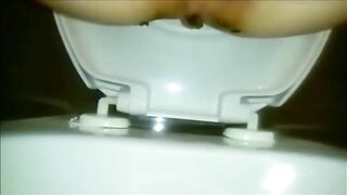 Woman shitting a long turd closeup in the toilet