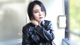 Woman in leather jacket squatting in a bathroom