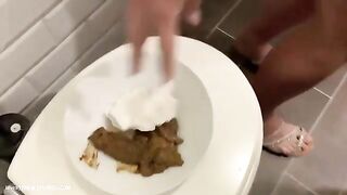 Blonde girl eats shit off a plate in a bathroom.