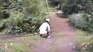 Man crouches in grass and eats his own shit