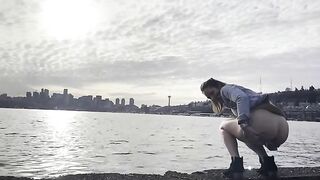 Girl squats by the water and pushes out a big shit