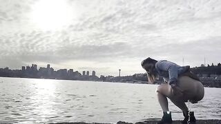 Girl squats by the water and pushes out a big shit