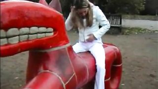 Girl in white dress takes a shit on a red dragon playground ride