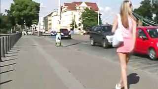 Girl in bikini pisses on a street pole in front of a tram