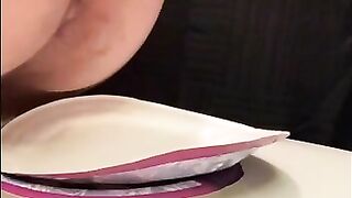 Girl stands over plate and shits on it